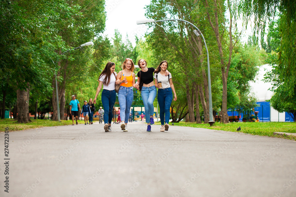Fototapeta premium Happy women in blue jeans walking in summer park