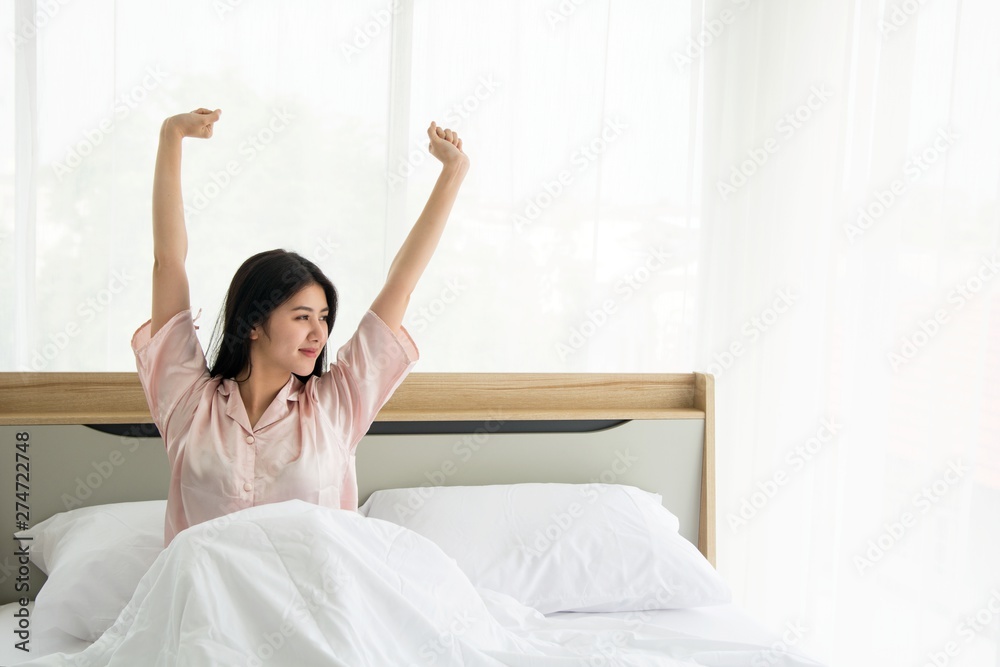 Portait of smiling lady wake up stretching herself welcome morning light on the bed Portait of smiling lady wake up stretching herself welcome morning light on the bed