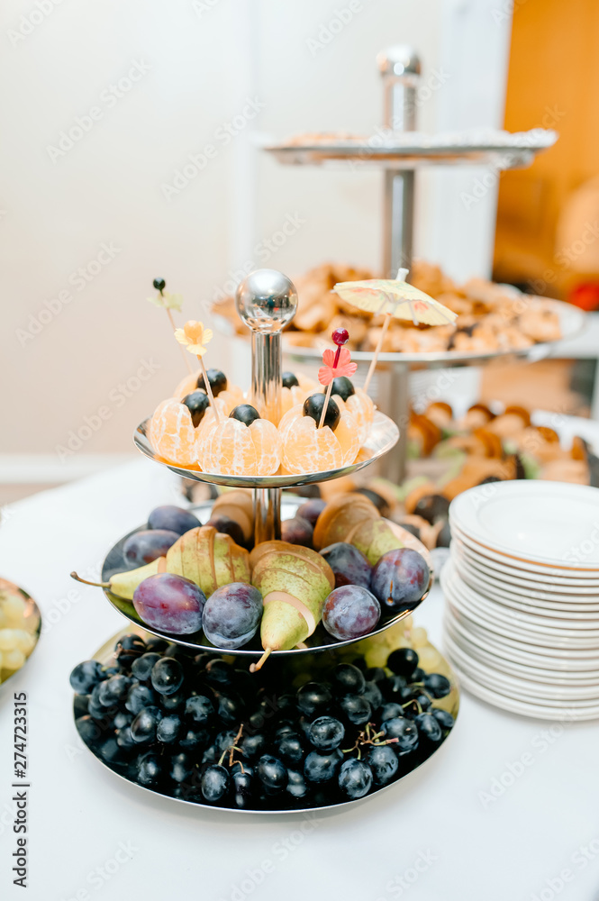 Candy bar. White wedding cake decorated by flowers standing of festive table with deserts, strawberry tartlet and cupcakes. Wedding. Reception Tartlets