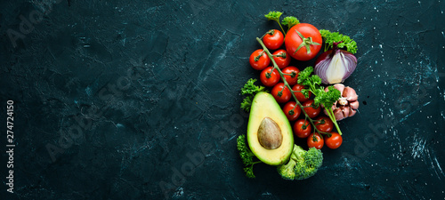 Fresh vegetables on a black background. Avocados, tomatoes, garlic, parsley, paprika. Top view. Free space for your text.