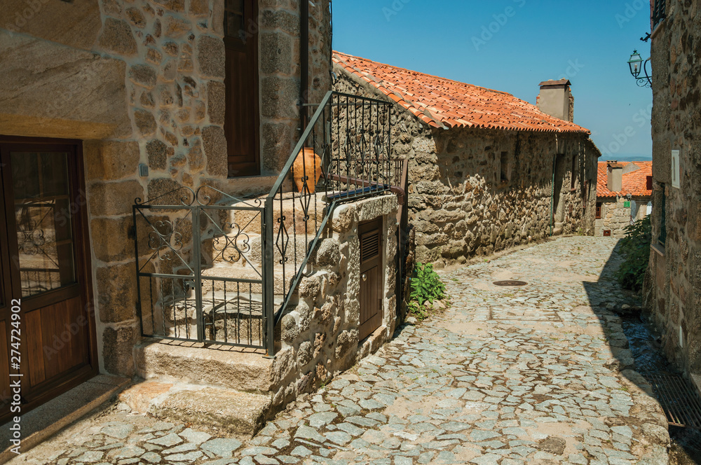 Cobblestone alley on slope and stone old houses