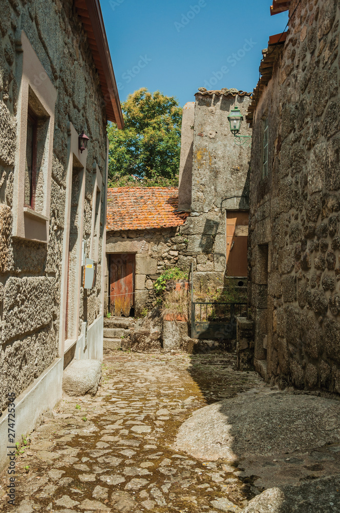 Narrow cobblestone alley on slope and stone old houses