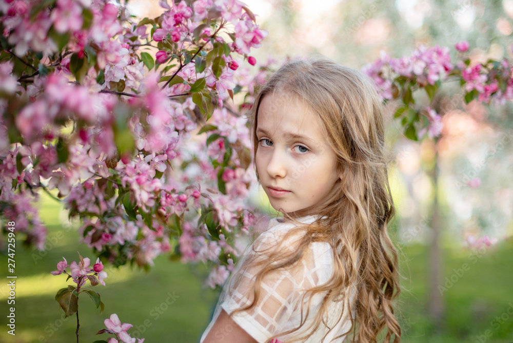 candid portrait of a girl in a blooming apple orchard
