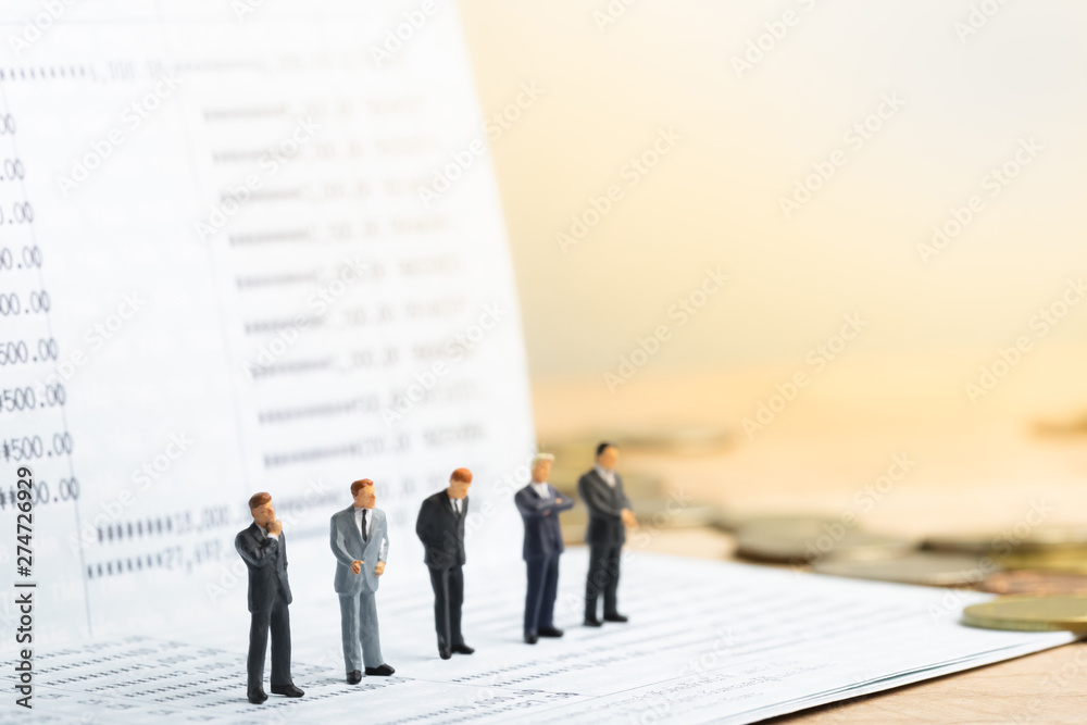 Small businessmans figures standing on turning point on bank passbook. Money saving and Investment concept. Business finance. Business teamwork. Small businessmans figures standing on turning point on bank passbook. Money saving and Investment concept. Business finance. Business teamwork.
