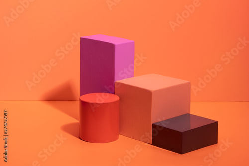 Geometric shapes in different colors on orange background. Three-dimensional solid figures on colored paper. photo