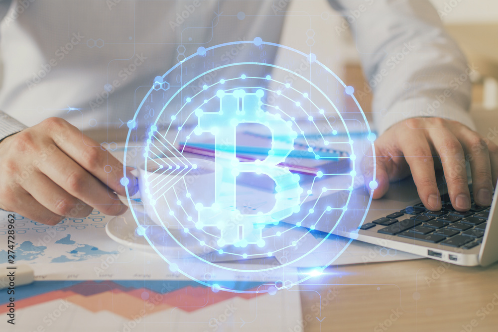 Crypto currency theme hologram with businessman working on computer on background. Concept of blockchain. Double exposure.