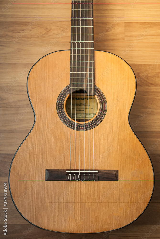 Acoustic guitar resting against a wooden background Acoustic guitar resting against a wooden background