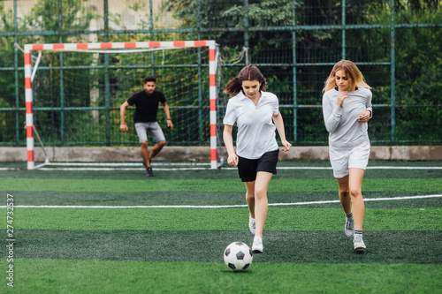 Stylish girls in a sportwear. Two women with ball. Girl play in socer, football game.