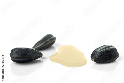 Several sunflower seeds and a puddle of sunflower oil. Isolated on the white background.