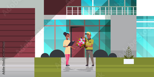 courier man giving bouquet of flowers to woman recipient express delivery service concept girl receiving parcel from african american deliveryman modern building exterior horizontal full length
