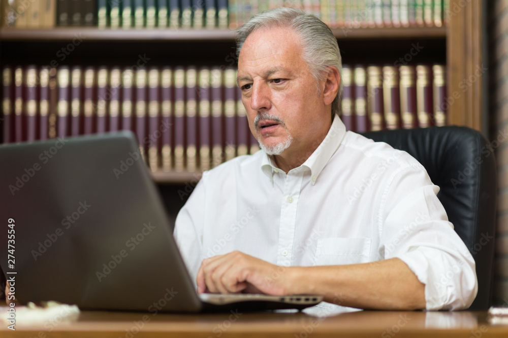 Businessman using his laptop in a library Businessman using his laptop in a library
