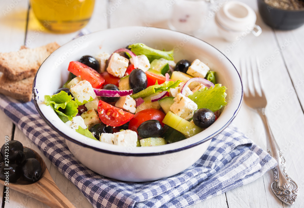 Delicious greek salad with feta cheese and olives in a white bowl