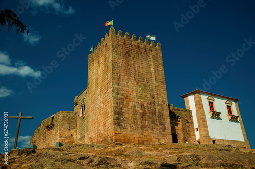 Castle and square tower over rocky hill with cross