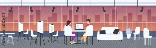 architects couple using laptop engineers drafting house project on computer screen with blueprints housing contractors designing house plan modern draftsman studio interior full length horizontal