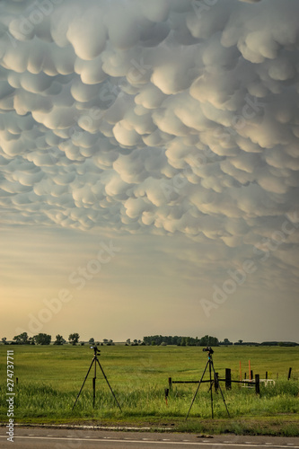 Tripods with equipment belonging to storm chasers below a thundery sky with mammatus clouds on the great plains, USA.