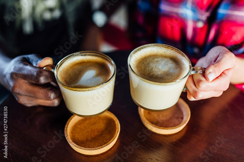 Close up photo. Two friends holding cup of coffee..