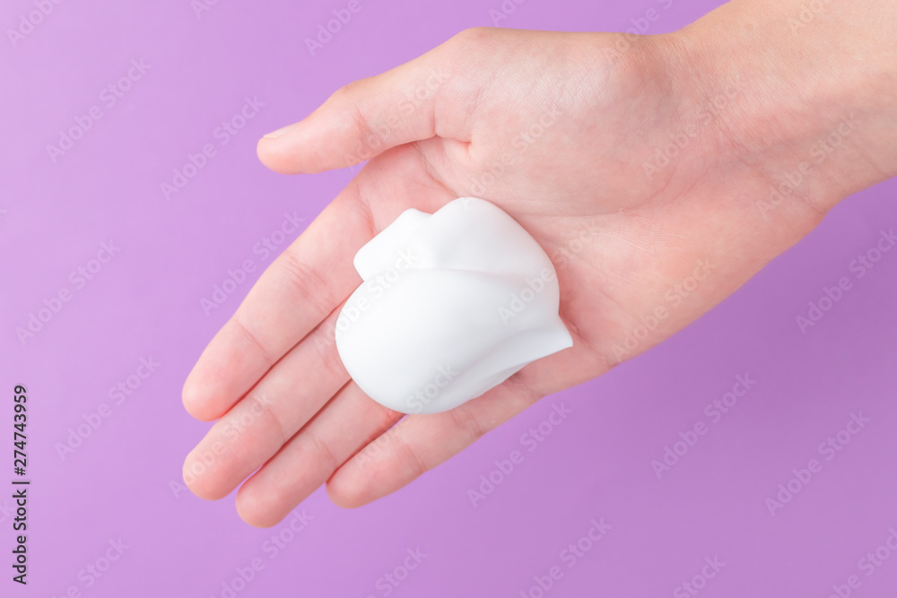 White shaving foam in the hand of a teenager on a blue bright background White shaving foam in the hand of a teenager on a blue bright background