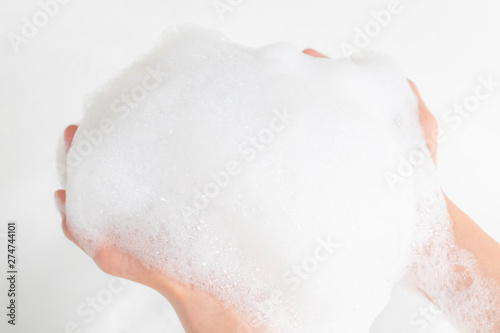 A lot of foam in the hands of a man in the bathroom