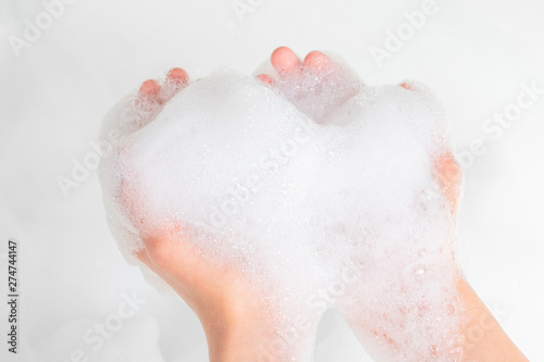 A pile of foam in the hands of a teenager in the bathroom