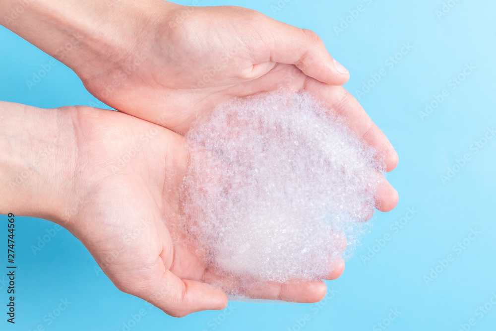 Two hands hold a bunch of foam while washing their face and body Two hands hold a bunch of foam while washing their face and body