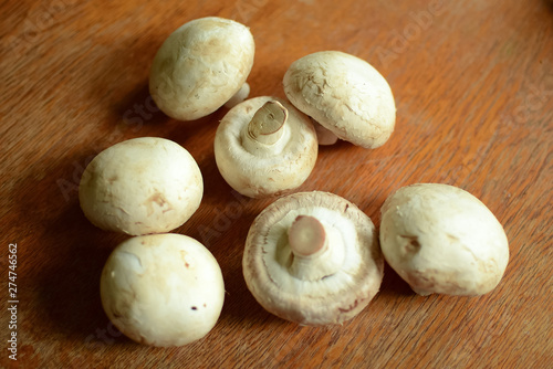 Champignon mushrooms lie on a wooden table.