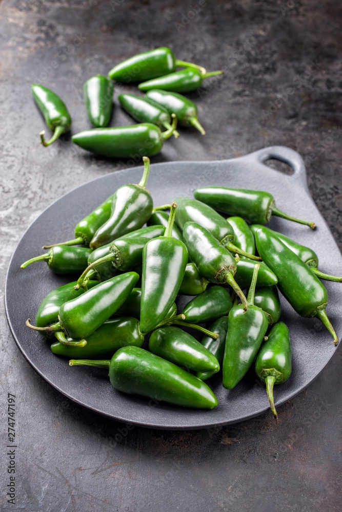 Frische rohe grüne scharfe Jalapeno Chili als closeup auf einem Teller mit Textfreiraum Frische rohe grüne scharfe Jalapeno Chili als closeup auf einem Teller mit Textfreiraum
