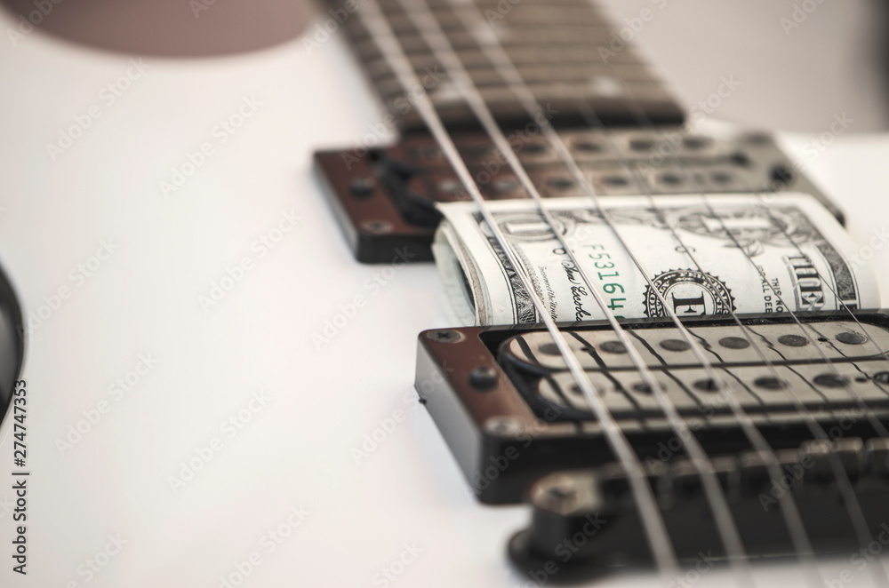 Fototapeta premium Guitar and one dollar banknote, top view, close-up, music and business concept