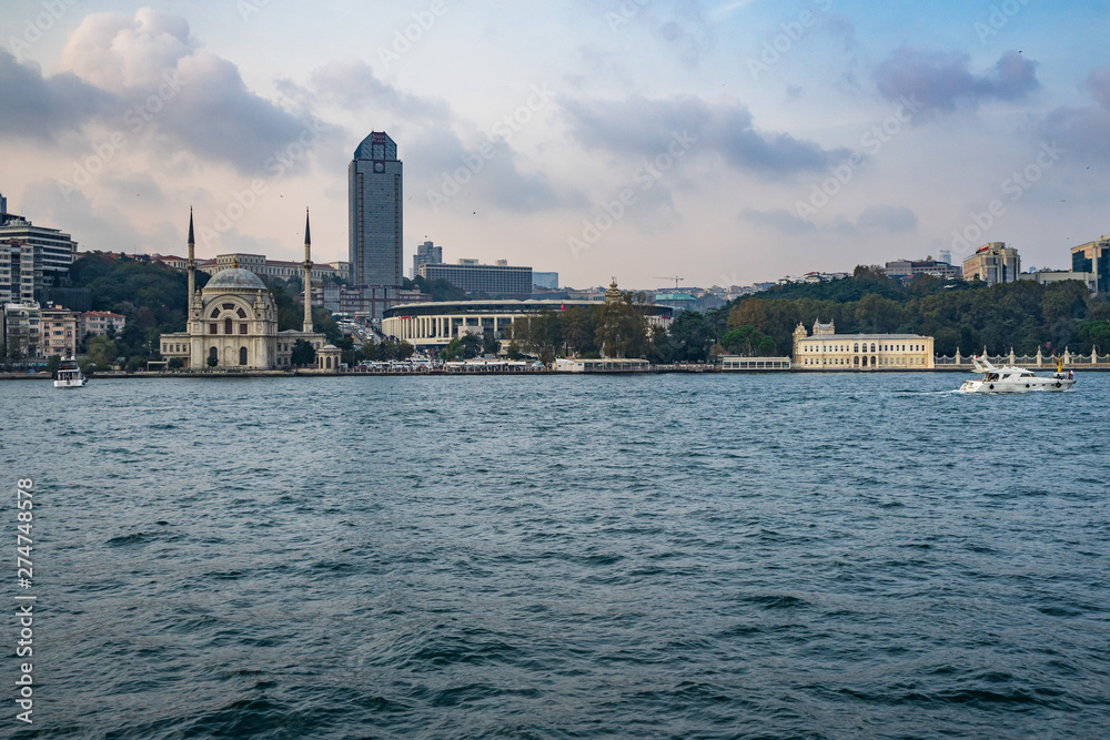 Dolmabahce mosque, Super Plaza Ritz-Carlton hotel and Vodafone Park stadium seen from a ferry boat cruising the Bosphorus strait, Istanbul, Turkey