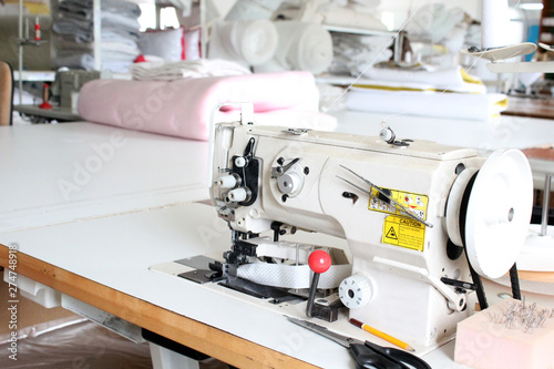 Professional sewing machine overlock in the workshop. Equipment for edging, hemming or stitching clothes in a tailor shop.