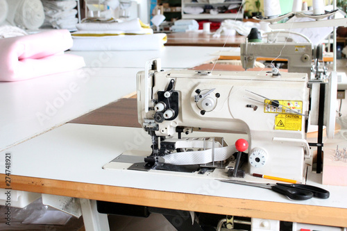 Professional sewing machine overlock in the workshop. Equipment for edging, hemming or stitching clothes in a tailor shop.