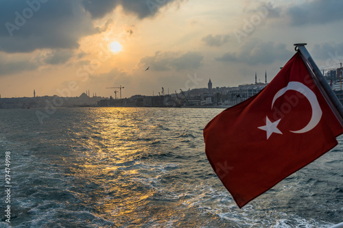 Turkish waving flag form a ferry cruising the Bosphours at sunset with Istanbul skyline in the background, Turkey