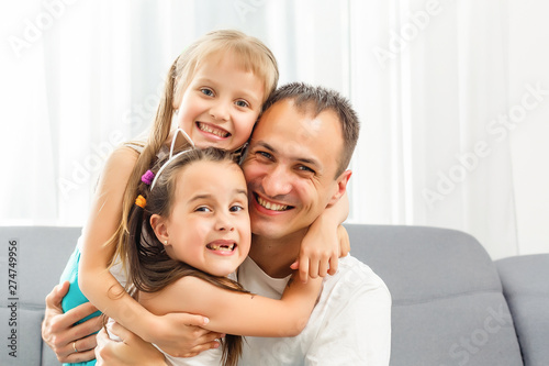 Happy dad carrying two little cute child girl on back giving kid piggyback ride having fun together, smiling single father playing with daughter embracing daddy laughing looking at camera, portrait © Angelov