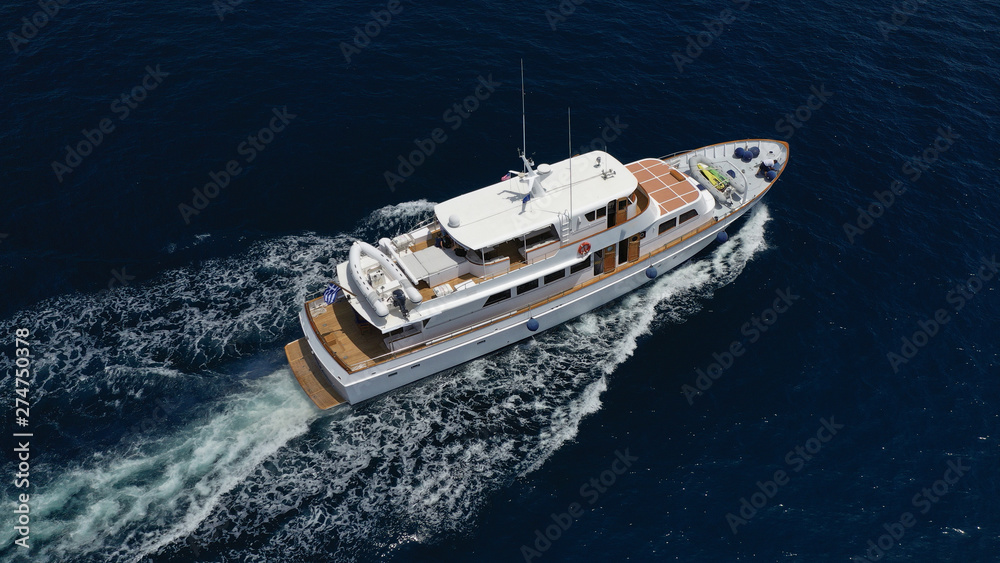 Aerial drone photo of luxury yacht cruising deep blue sea in Mediterranean Aegean island destination located in Greece