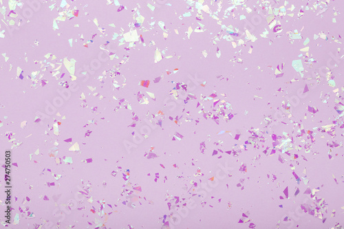 Glowing mica sparkles on pastel violet trendy background. Festive abstract backdrop with confetti. Flat lay.