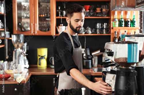 Portrait of barista using coffee grinding machine in cafe