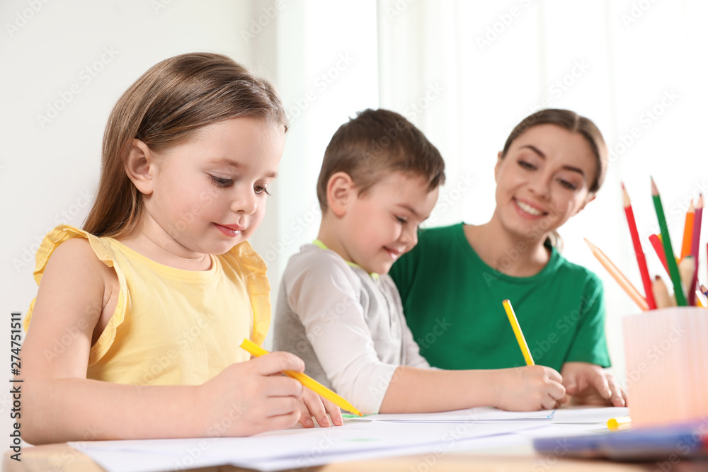 Little children with kindergarten teacher drawing at table indoors. Learning and playing Little children with kindergarten teacher drawing at table indoors. Learning and playing