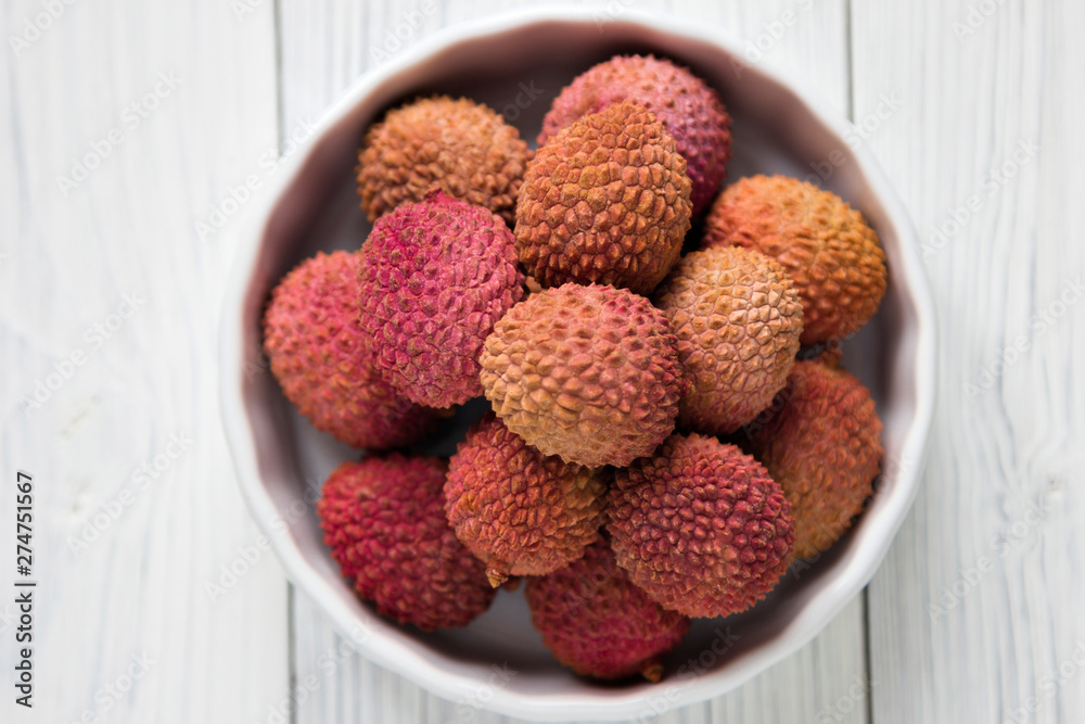 Fresh lychee in white bowl on a wooden background Fresh lychee in white bowl on a wooden background