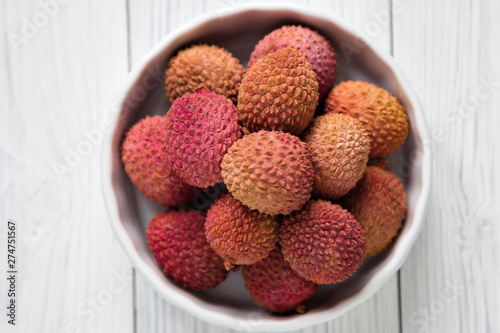 Fresh lychee in white bowl on a wooden background