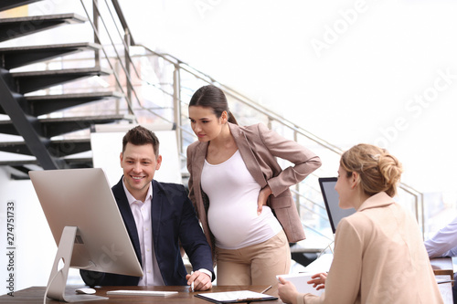 Young pregnant woman working with her employees in office © New Africa
