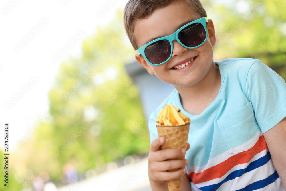 Cute little boy with delicious ice cream outdoors, space for text