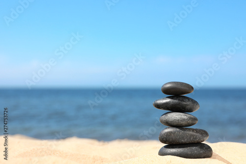 Stack of stones on sand near sea, space for text. Zen concept
