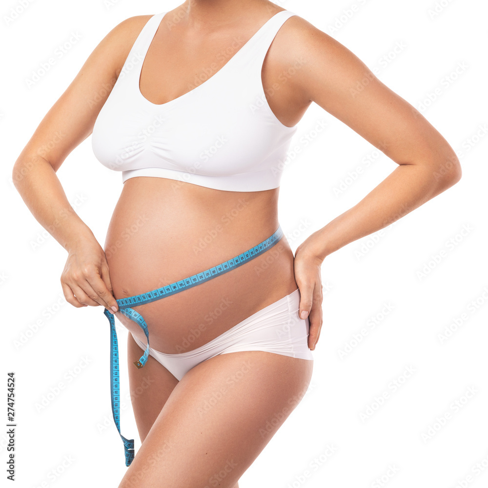 Pregnant woman with measuring tape is checking her belly girth