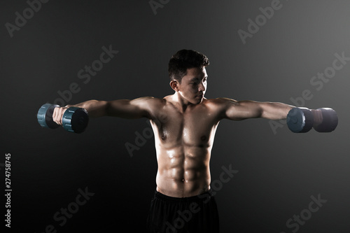 Asian man exercising his biceps with dumbbells © Creativa Images