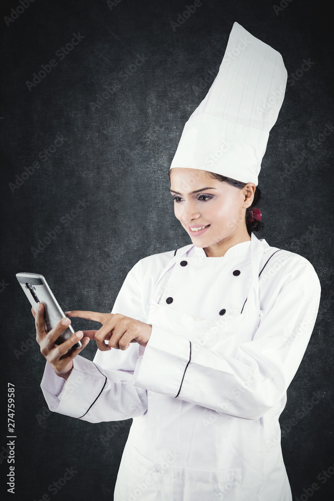 Beautiful female chef using a mobile phone Beautiful female chef using a mobile phone