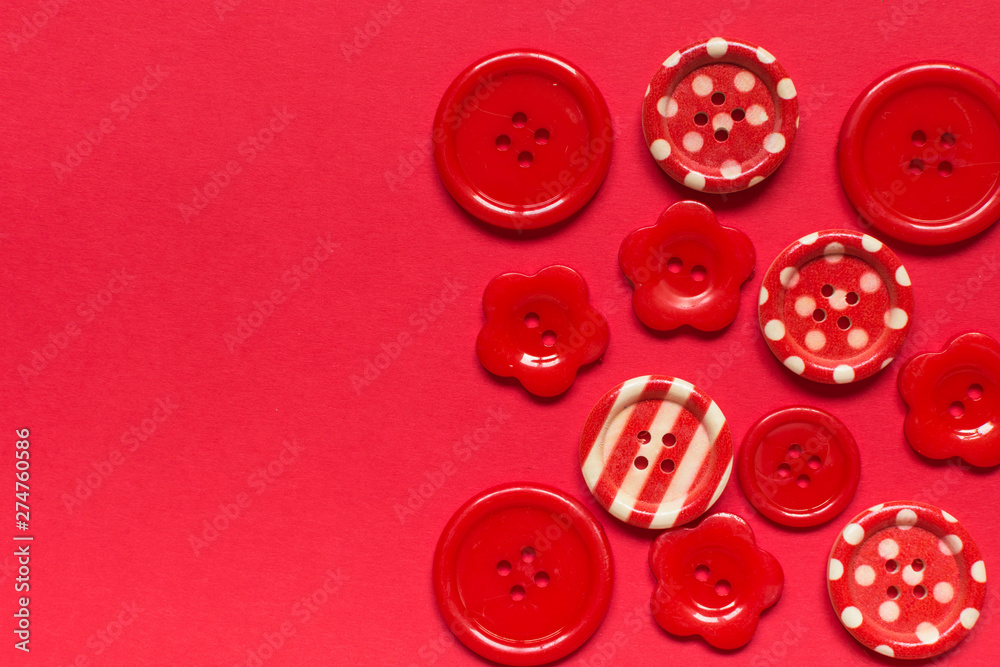 Fototapeta premium Various red sewing buttons on red background