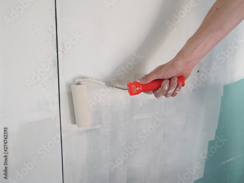  priming the walls in the house with a roller in the repair
