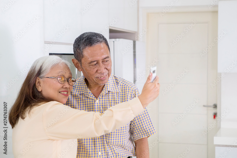 Obraz premium Elderly couple taking a selfie together at home