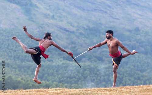 Indian fighters performing Weapon Combat during Kalaripayattu Marital art demonstration in Kerala, India photo