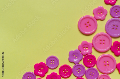 Various pink sewing buttons on light yellow background