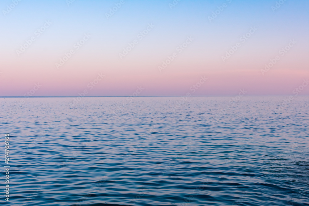 Obraz premium Seascape background, a hazy colorful sunset after a hot summer day over calm sea water, Vis island, Croatia